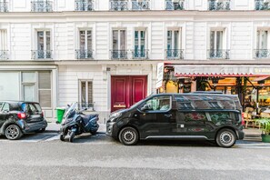 Ein schwarzer Van parkt auf einer Straße, im Hintergrund ein Gebäude mit weißen Fassaden und Balkonen.