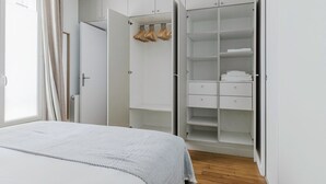 A bedroom with a bed, a wardrobe, and a window with curtains.
