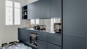 A modern kitchen with grey cabinets, a black countertop, and a window providing natural light.