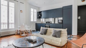 A modern living room with a sofa, coffee table, and dining area.
