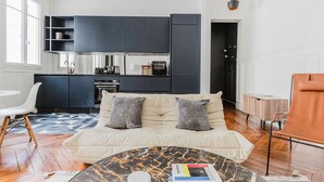 A modern living room with a sofa, a coffee table, and a kitchen area in the background.