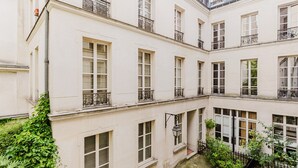 A multi-story building with a courtyard, featuring balconies with wrought iron railings and large windows. - Blueground | Le Marais-Republique, nr restaurants (Paris)