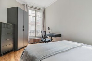 Une chambre à coucher comprenant un lit, un bureau, une chaise et une armoire.