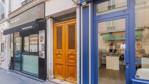 A storefront with a black awning, a wooden door with a lattice pattern, and a blue-framed window.