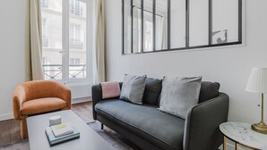A modern living room with a sofa, a chair, a coffee table, and a lamp.