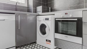 A compact kitchen with a washing machine, dishwasher, and oven.