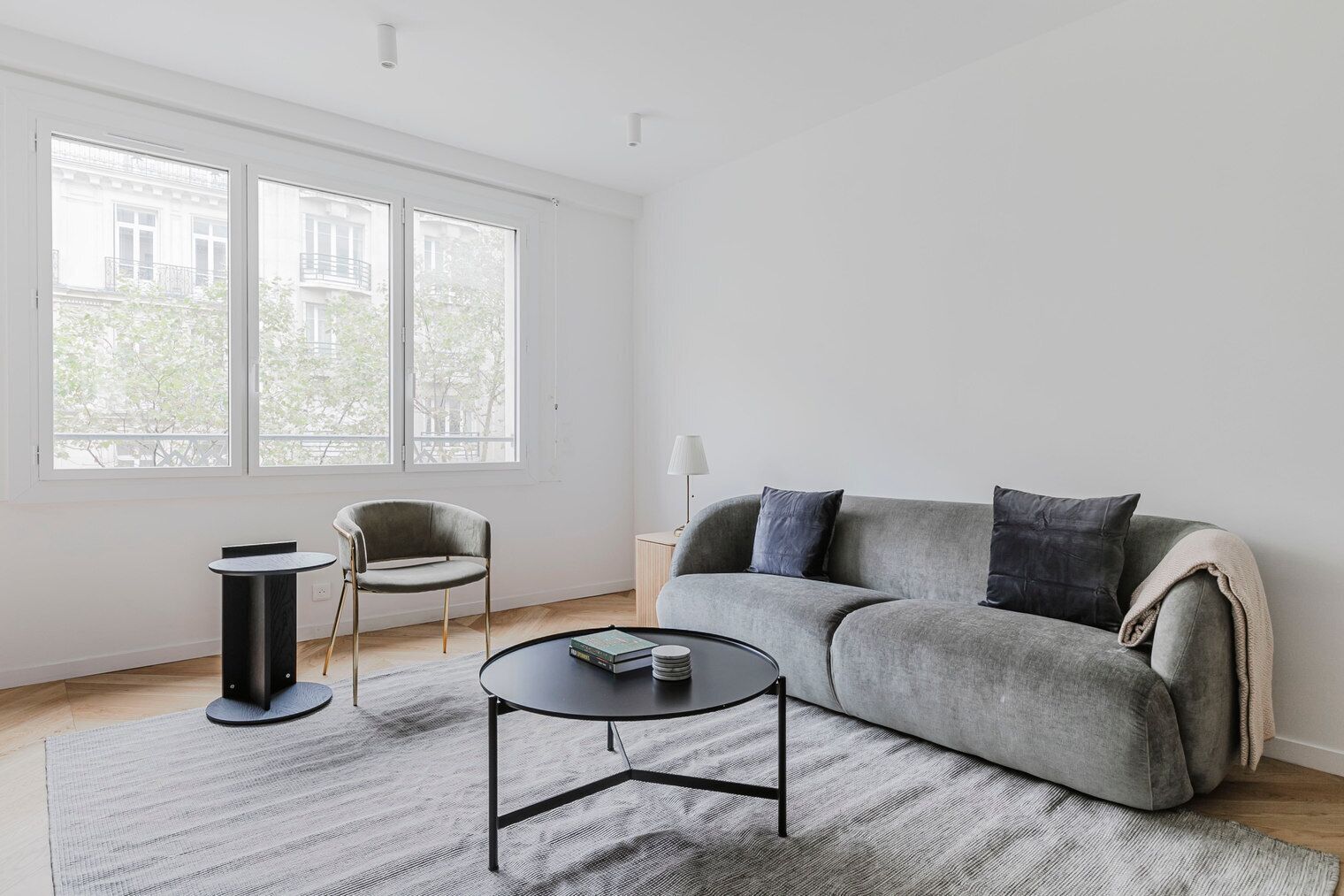 Ett modernt vardagsrum med en grå soffa, ett runt soffbord och ett litet sidobord.