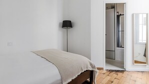 A bedroom with a bed, a floor lamp, and a door leading to a bathroom. - Blueground | Porte Dauphine, elev, nr metro (Paris)