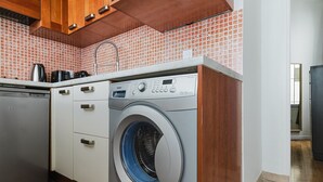 A compact kitchen with a built-in washing machine, a dishwasher, and a coffee maker. - Blueground | Porte Dauphine, elev, nr metro (Paris)