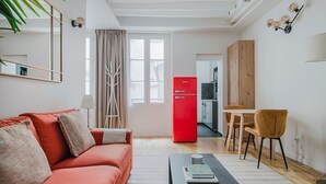 Un salon moderne avec un canapé rouge, une table basse et un coin repas comprenant une table et des chaises en bois.
