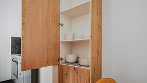Une cuisine avec un meuble en bois contenant des bols et des assiettes blancs.