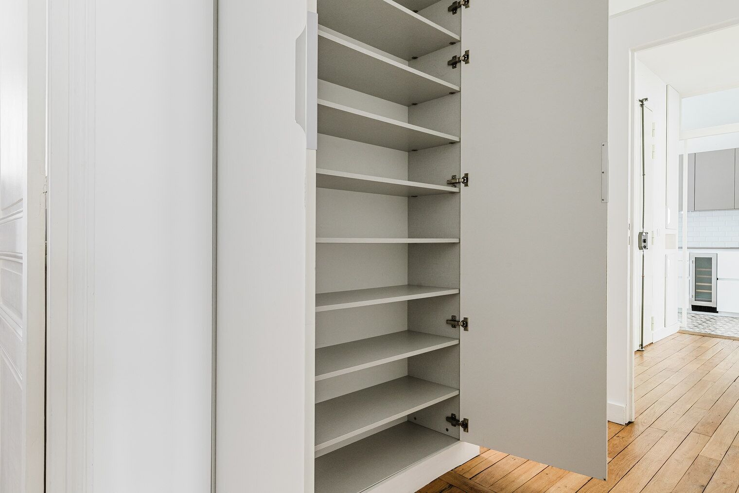 Een witte kast met meerdere planken en een deur.