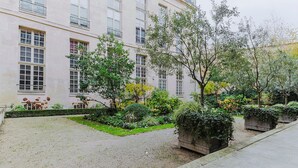 Un edificio con múltiples ventanas y un jardín con diversas plantas y árboles.