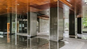 Un hall d’entrée moderne avec un sol carrelé brillant, un plafond en bois et des murs en verre.