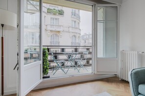 Une pièce dotée d’une grande porte-fen être coulissante donnant sur un balcon aménagé avec du mobilier d’extérieur.