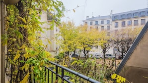A balcony with a view of a cityscape, featuring buildings and trees. - Blueground | Le Marais, elevator & w/d, nr Seine (Paris)