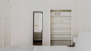 A bedroom with a bed, a large mirror, and a walk-in closet with shelves and hanging space. - Blueground | Le Marais, elevator & w/d, nr Seine (Paris)