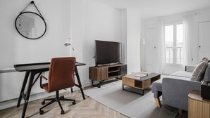 Una sala de estar moderna con una televisión de pantalla plana, un sillón de cuero marrón, un sofá gris y una mesa de centro de madera.