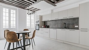 A modern kitchen with white cabinets, a black countertop, and a dining area with a round table and chairs.