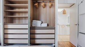 A modern, open-plan bedroom with a built-in wardrobe, a small seating area, and a view of a balcony. - Blueground | Le Marais, elevator & w/d, nr Vosges (Paris)