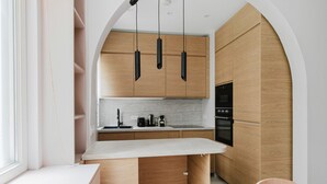 A modern kitchen with wooden cabinets, a white countertop, and a built-in oven. - Blueground | Auteuil, washer, nr Monceau Park (Paris)