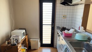 Ett kompakt kök med mikrovågsugn, vattenkokare och diskho.