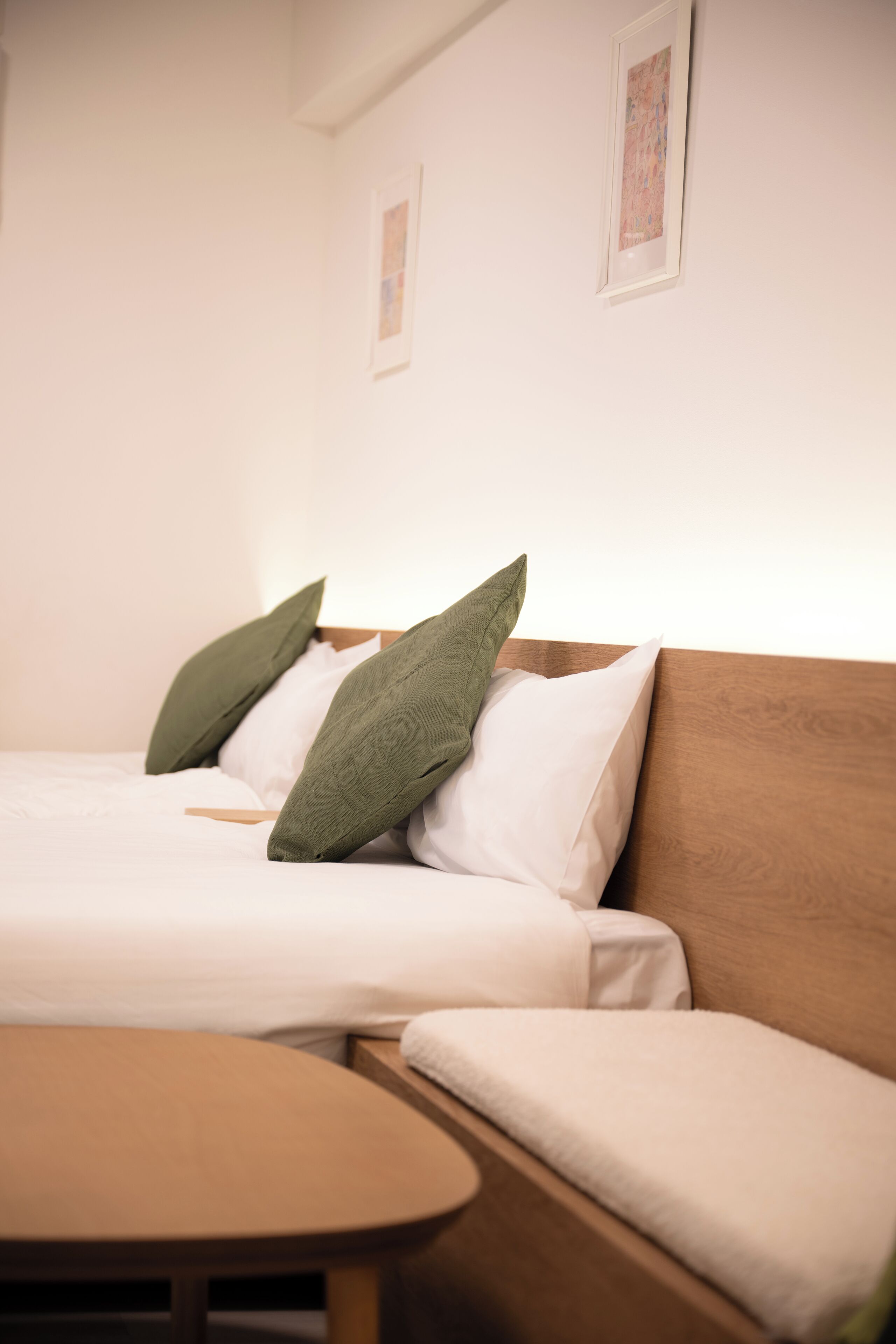 A neatly arranged hotel room with a bed, a wooden headboard, and a small table.