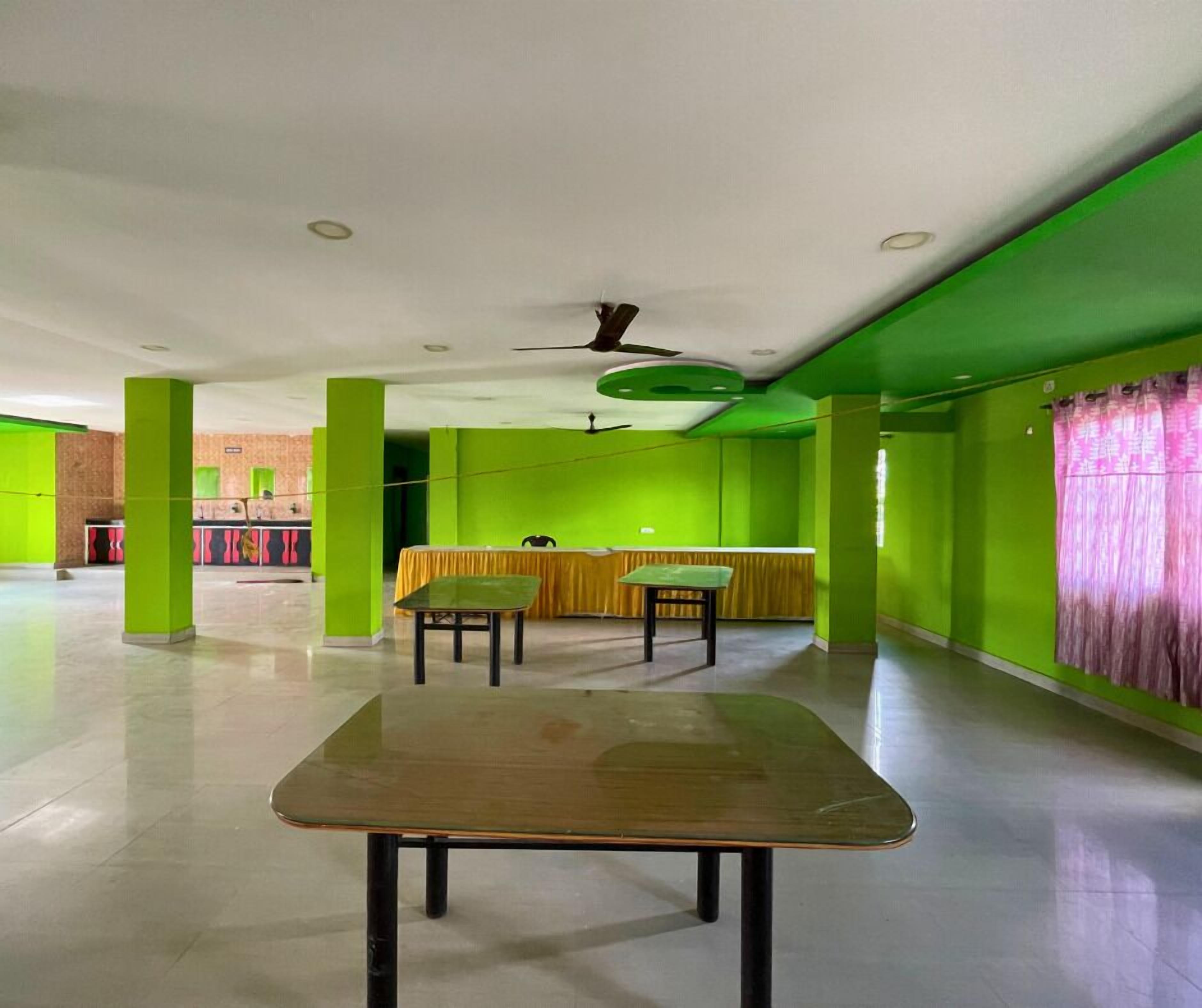 A spacious room with green walls, a ceiling fan, and a table with chairs.