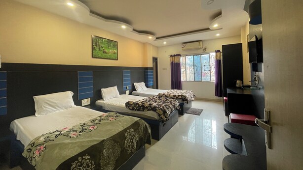 A hotel room with two beds, a TV, a painting, and a window with curtains.