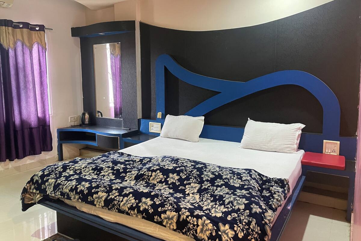 A bedroom with a bed, a nightstand, a dresser, a mirror, and a window with curtains.