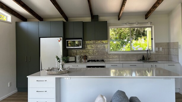 Una cocina moderna con una isla central, electrodomésticos integrados y un amplio ventanal con vistas al verdor.