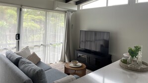 Una sala de estar moderna con un sofá gris, un televisor de pantalla plana y una mesa de comedor con adornos decorativos.