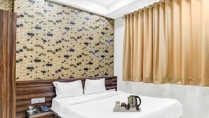 Een hotelkamer met een bed, houten hoofdbord, nachtkastje en een muur met een mozaïekpatroon.