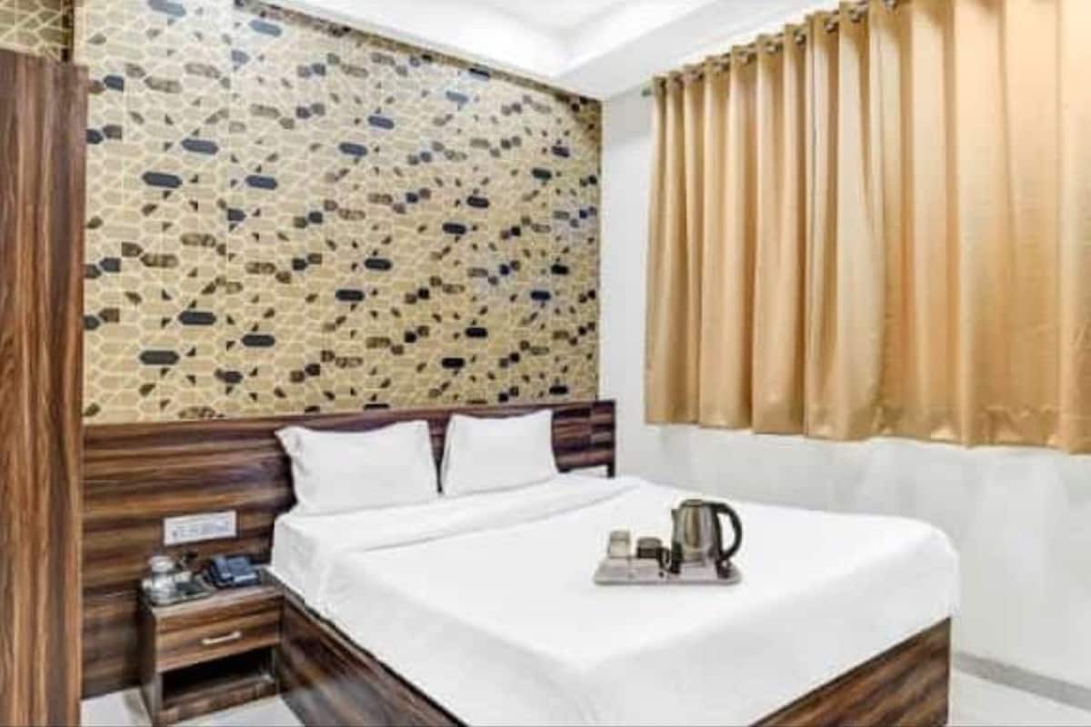 A hotel room with a bed, wooden headboard, a nightstand, and a wall with a mosaic pattern.