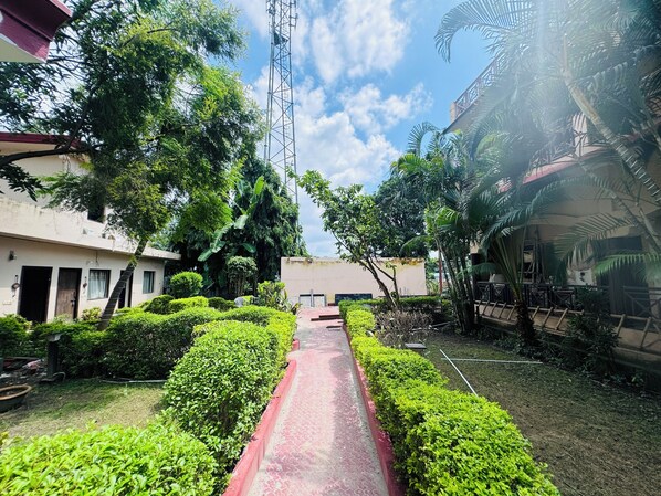 Un sendero bordeado por setos bien cuidados y un edificio con balcón.