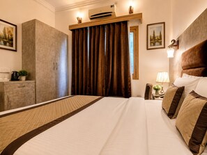 A hotel room with a large bed, a wardrobe, a desk with a lamp, and a window with curtains. - Staybook The Rudveda Resort (Ramnagar)