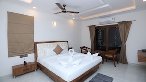 Une chambre d’hôtel moderne équipée d’un grand lit, d’un bureau, d’une chaise, d’un ventilateur de plafond et d’un appareil de climatisation.
