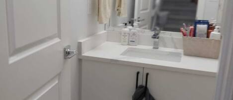 A small, white bathroom with a single sink, a mirror, and a towel rack.