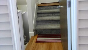 Un pasillo estrecho con una escalera alfombrada que lleva a una puerta blanca.