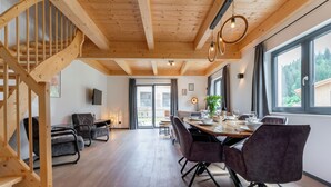 Un comedor amplio con escaleras de madera, muebles modernos y ventanas grandes que ofrecen vistas al exterior.