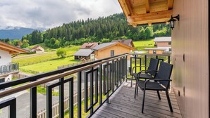 Un balcón de madera con vistas a un paisaje verde y casas.