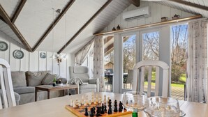Ein gemütliches Zimmer mit Holztisch, Schachbrett und Blick ins Freie.