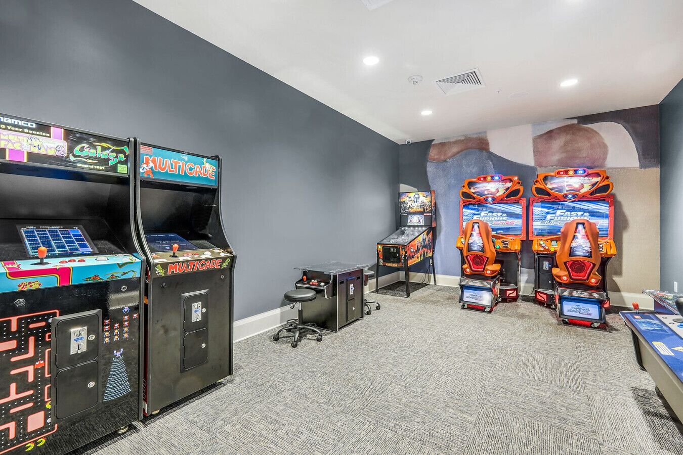 A room with arcade machines, including 'Multicade' and 'Fast Fury'.