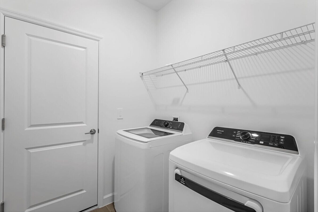 Un cuarto de lavandería con una puerta blanca, una lavadora y una secadora.