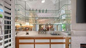 A modern kitchen with a glass-fronted wine rack, wooden cabinets, and a built-in stove. - Woodhaven Great Views on the Golf Course (Palm Desert)