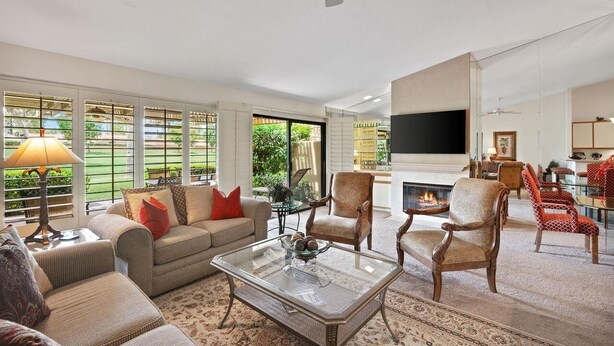 A spacious living room with a sofa, armchairs, a coffee table, and a fireplace. - Woodhaven Great Views on the Golf Course (Palm Desert)