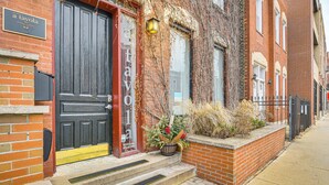 A brick building with a black door, a sign reading "a tavola Italian classic," and a small planter with dried plants on the steps. - 5 Mi to Dtwn: Ukrainian Village Apartment! (Chicago)
