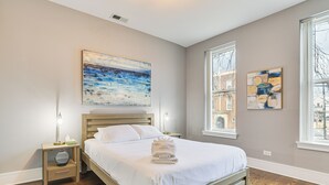 A bedroom with a wooden bed, a nightstand with a lamp, and two abstract paintings on the walls. - 5 Mi to Dtwn: Ukrainian Village Apartment! (Chicago)