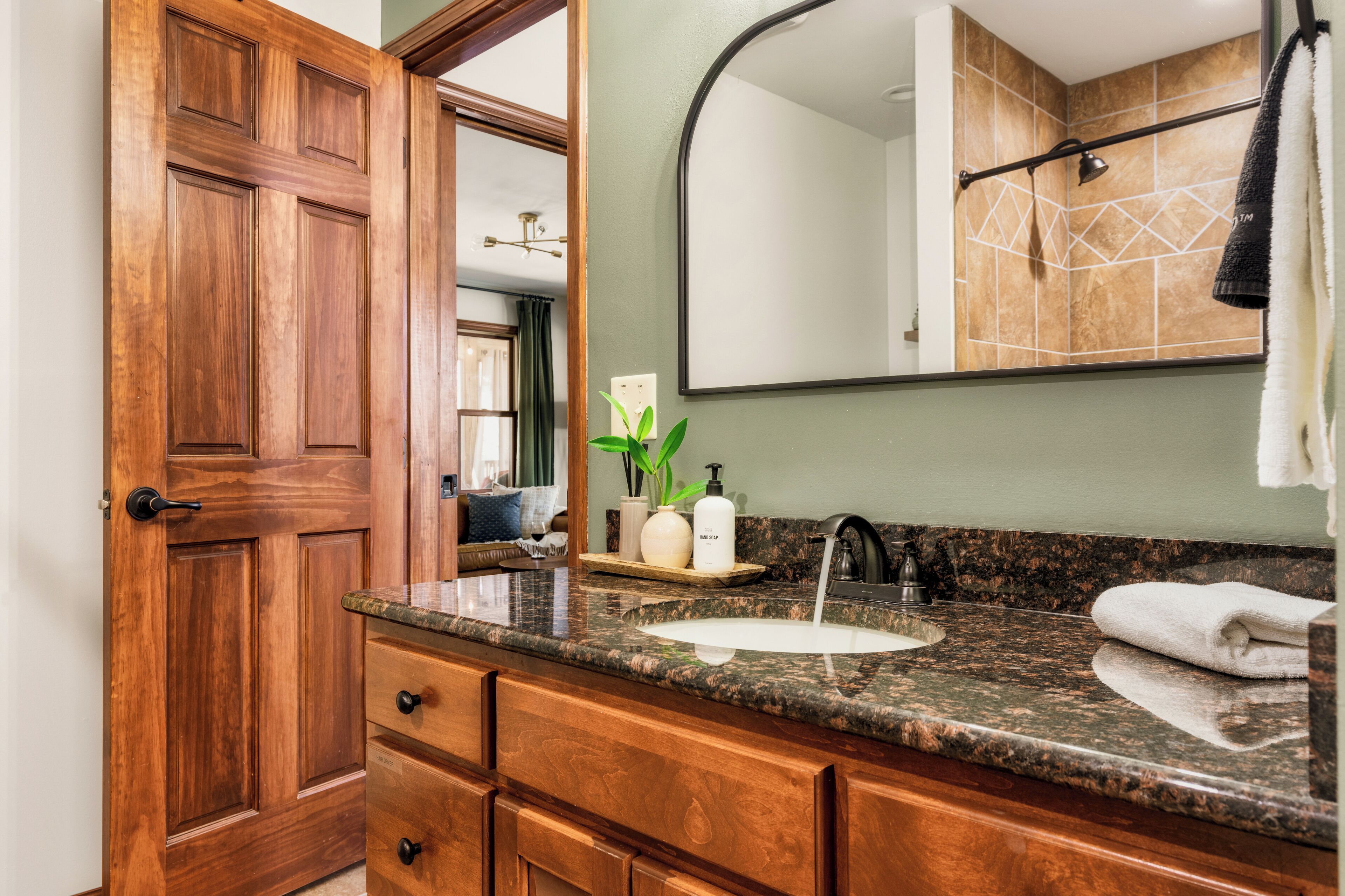 A bathroom with a wooden vanity, a sink, a mirror, and a towel rack.