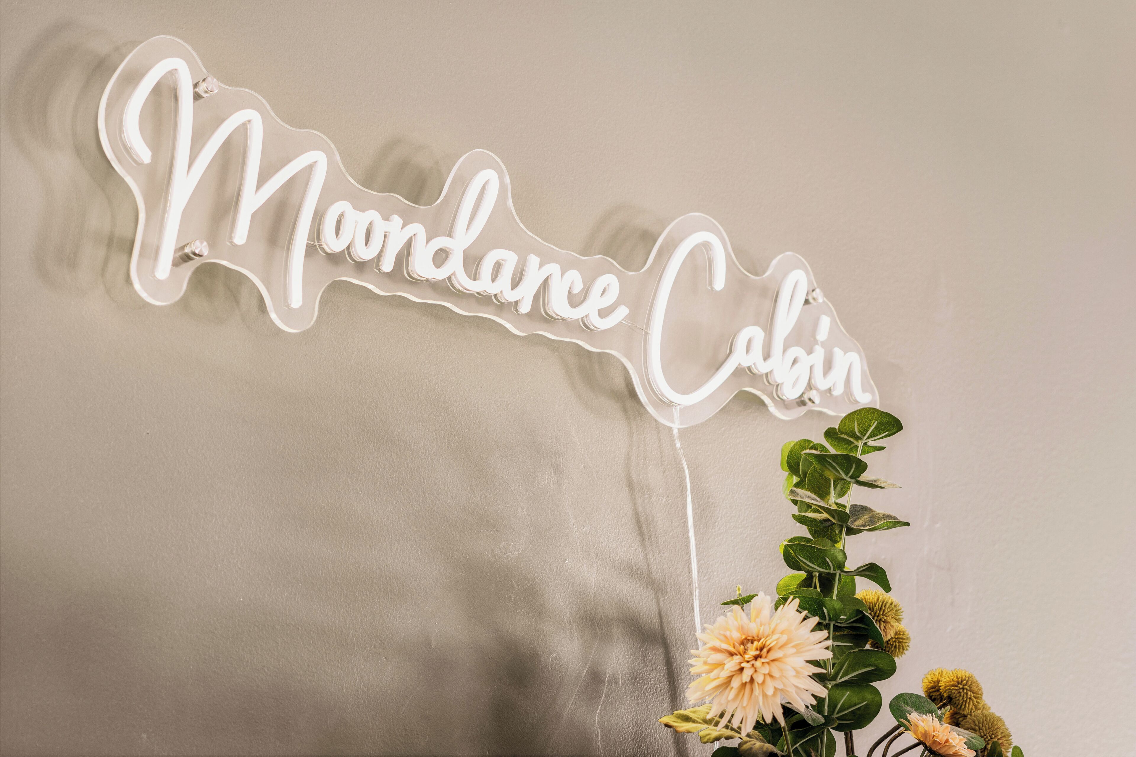 A neon sign with the text "Mondance Cabin" on a plain wall.